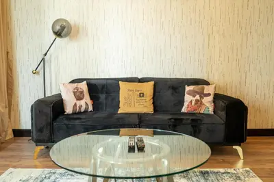 a living room with a black couch and a glass table at BellaVista 29 Boulevard 1 Bedroom Apartment with Extra Bedroom Partial Fountain Views in Dubai