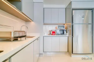a kitchen with white cabinets and a refrigerator at Splendid 2BR at Sunrise Bay Tower 1 Emaar Beachfront Dubai Marina by Deluxe Holiday Homes in Dubai