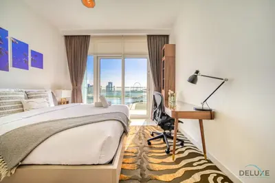 a bedroom with a bed and a desk and a window at Splendid 2BR at Sunrise Bay Tower 1 Emaar Beachfront Dubai Marina by Deluxe Holiday Homes in Dubai