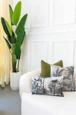 a white couch with two pillows and a plant at ON OFF HH- CREEK HARBOUR-Lavish Parisian 2 BR in Dubai