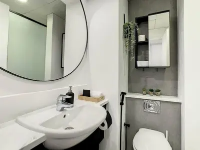 a bathroom with a sink and a mirror and a toilet at Luxury Modern Studio in JLT - Rooftop Pool - Lake Area Upgrades Ongoing in Dubai