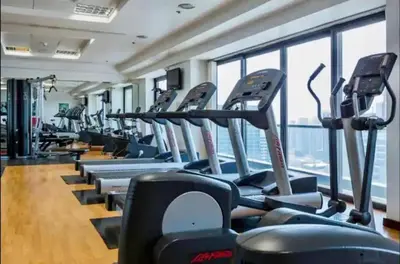 a gym with rows of treadmills and a large window at Luxury Modern Studio in JLT - Rooftop Pool - Lake Area Upgrades Ongoing in Dubai