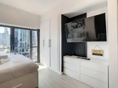 a white bedroom with a bed and a large window at Luxury Modern Studio in JLT - Rooftop Pool - Lake Area Upgrades Ongoing in Dubai