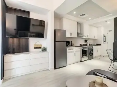 a large white kitchen with a large tv on the wall at Luxury Modern Studio in JLT - Rooftop Pool - Lake Area Upgrades Ongoing in Dubai