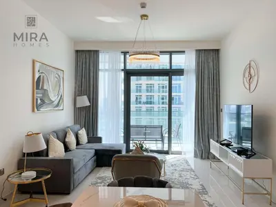 a living room with a couch and a large window at Mira Holiday Homes - Newly 1 bedroom apartment with beach access in Dubai