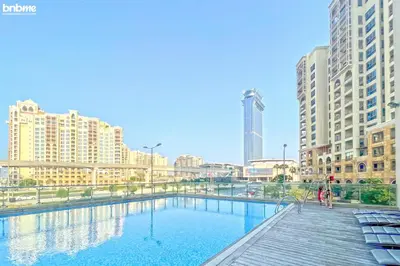 a large swimming pool in a city with tall buildings at bnbme - Palm Jumeirah Studio Balcony Sea Ain Dubai Views Pool Gym Parking Access in Dubai