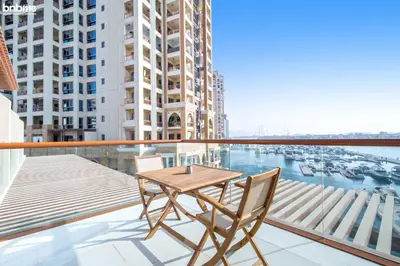 a wooden table and chairs on a balcony with a harbor at bnbme - Palm Jumeirah Studio Balcony Sea Ain Dubai Views Pool Gym Parking Access in Dubai
