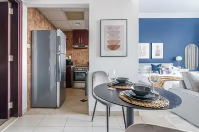 a kitchen and living room with a table and a refrigerator at GuestReady - Chic Studio in Urban JLT in Dubai