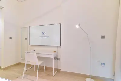a white desk with a chair and a whiteboard on a wall at Luxury Escapes - Brand New Studio with View - Azizi Farhad Jaddaf in Dubai