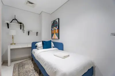 a white bedroom with a blue bed and a desk at GuestReady - Stylish Galore near Dubai Fountain in Dubai
