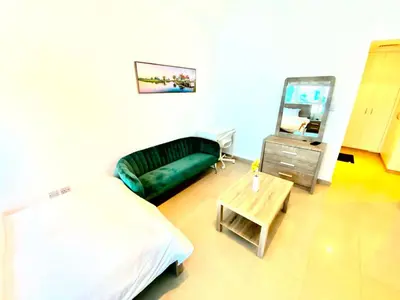 a bedroom with a bed and a couch and a mirror at Marina Crown Tower Stays Hostel for Girls in Dubai