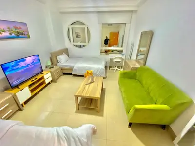a living room with a green couch and a television at Marina Crown Tower Stays Hostel for Girls in Dubai
