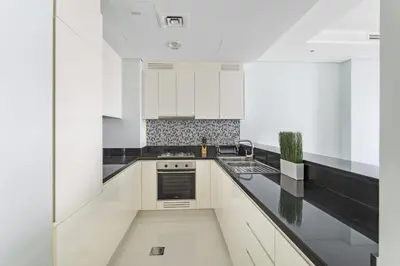 a kitchen with white cabinets and black counter tops at ALiving Luxury 2BR with Infinity Pool I Near Dubai Mall & Burj Khalifa I Paramount Hotel Midtown in Dubai