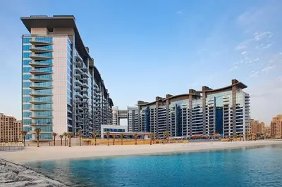 a building on the beach next to a body of water at Livbnb Suites - 1BR with Sea View & Beach Access in Dubai