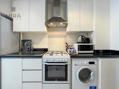 a kitchen with a stove and a washing machine at Mira Holiday Homes - Newly serviced apartment in Dubai South in Dubai