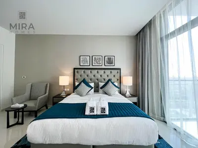 a bedroom with a large bed and a chair at Mira Holiday Homes - Newly serviced apartment in Dubai South in Dubai
