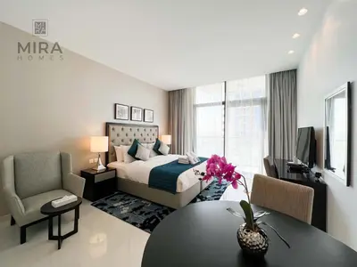 a bedroom with a bed and a table and a chair at Mira Holiday Homes - Newly serviced apartment in Dubai South in Dubai