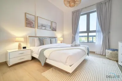 a white bedroom with a large bed and a window at Placid 1BR at La Cote 5 Jumeirah 1 by Deluxe Holiday Homes in Dubai