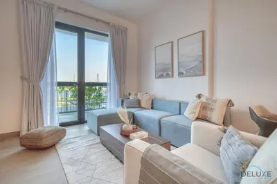 a living room with a blue couch and a large window at Placid 1BR at La Cote 5 Jumeirah 1 by Deluxe Holiday Homes in Dubai
