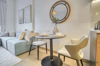 a living room with a table and chairs and a couch at Placid 1BR at La Cote 5 Jumeirah 1 by Deluxe Holiday Homes in Dubai