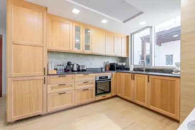 a kitchen with wooden cabinets and a large window at Downtown Luxury I 5 Min Walk To Dubai Fountain! in Dubai