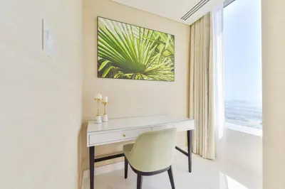 a white desk and a chair in a room with a window at Ultra Luxury Palm Tower with Shared Hotel Facilities in Dubai