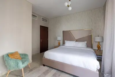 a bedroom with a large white bed and a chair at Bellavista - Glamorous - 2BR - 29 Boulevard - Burj Khalifa & Fountain View in Dubai