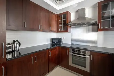 a kitchen with wooden cabinets and a stove top oven at Bellavista - High Floor - 1BR - 29 Boulevard - Full Burj Khalifa & Fountain View in Dubai