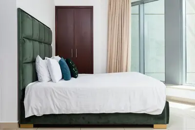 a bedroom with a large bed with a green headboard at Bellavista - High Floor - 1BR - 29 Boulevard - Full Burj Khalifa & Fountain View in Dubai
