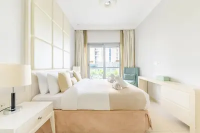 a white bedroom with a bed and a window at Damac Mall Street Residences in Dubai