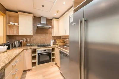 a kitchen with a stainless steel refrigerator and wooden cabinets at Luxury Beachfront Palm Jumeirah I Free 5 Star Beach Resorts Access in Dubai