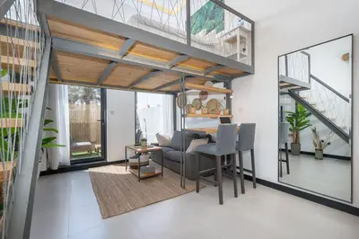 a living room with a table and chairs and stairs at Tropical Loft with working station in JVC in Dubai