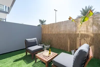 a patio with two chairs and a table and a fence at Tropical Loft with working station in JVC in Dubai