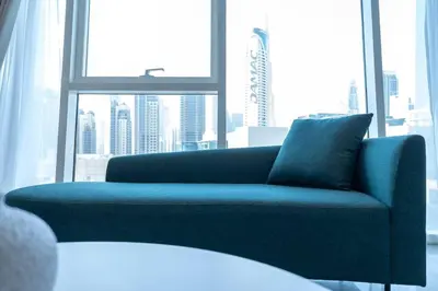 a blue couch in a room with a large window at Cosmopolitan Apartment with Burj Khalifa View in Dubai