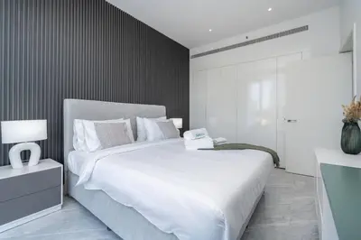 a bedroom with a large white bed and a black wall at Cosmopolitan Apartment with Burj Khalifa View in Dubai