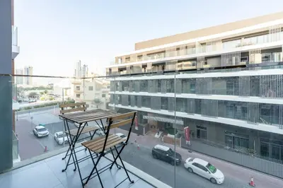 a balcony with a wooden table and a building at Cozy studio in heart of Dubai - JVC in Dubai