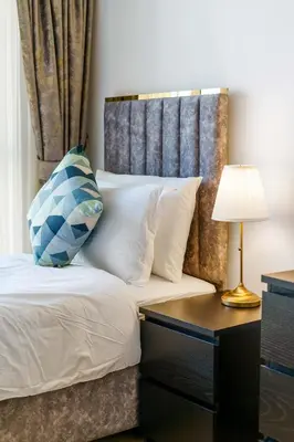 a bed with a headboard and a table with a lamp at 2BR in JBR / Sea View / Dubai Marina / Walk2Beach in Dubai