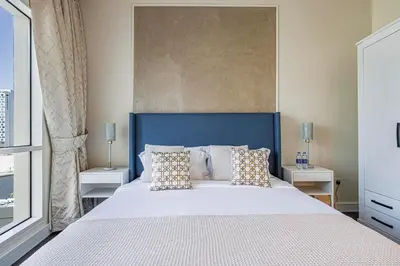 a bedroom with a large bed with a blue headboard at Daniels 1BR Business Bay Partial Burj Khalifa View in Dubai