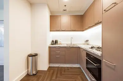 a kitchen with brown cabinets and a refrigerator at Daniels 1BR Business Bay Partial Burj Khalifa View in Dubai