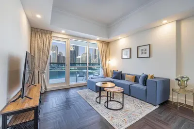 a living room with a blue couch and a large window at Daniels 1BR Business Bay Partial Burj Khalifa View in Dubai