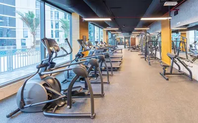 a row of treadmills in a gym with a large window at Expo Village Serviced Apartments in Dubai