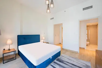 a bedroom with a white bed and a blue headboard at Expo Village Serviced Apartments in Dubai