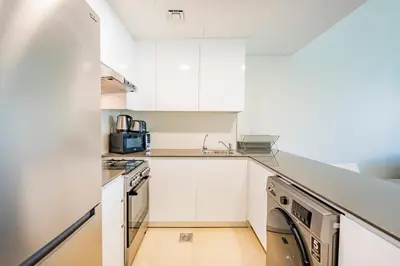 a kitchen with white cabinets and a sink at Expo Village Serviced Apartments in Dubai