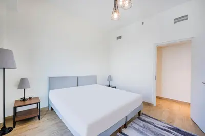 a bedroom with a large white bed and a table at Expo Village Serviced Apartments in Dubai