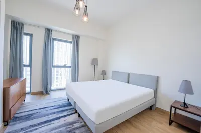 a white bedroom with a large bed and windows at Expo Village Serviced Apartments in Dubai