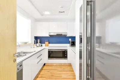 a kitchen with white cabinets and a blue wall at Al Bateen · Ultra Luxury JBR · Private Beach and Pool in Dubai