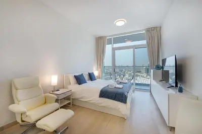 a bedroom with a bed and a tv and a chair at Spectacular Views of Dubai Skyline in Dubai