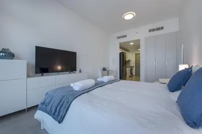 a white bedroom with a large bed with a flat screen tv at Spectacular Views of Dubai Skyline in Dubai