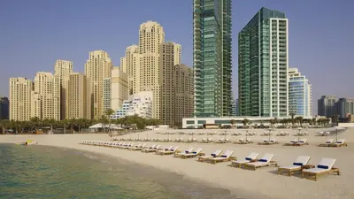 a beach with chaise lounges and chairs and buildings at Luxury JBR Shams - Marina View - Free 5 star Beach Resorts Access! in Dubai