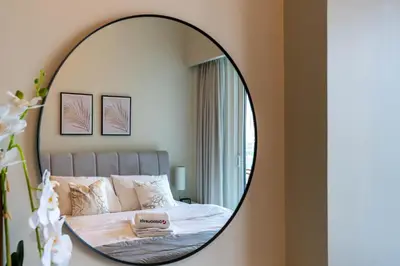 a mirror in a bedroom with a bed at Gala Guests - Marasi Drive City View Apartments in Dubai